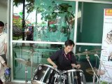 Drummer performing beside a glass-fronted studio space